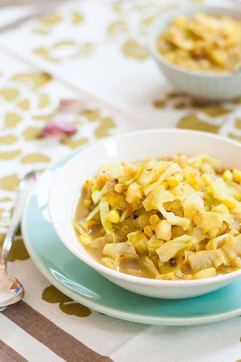 Vertical image of a curried cabbage soup in bowls on tablecloth.
