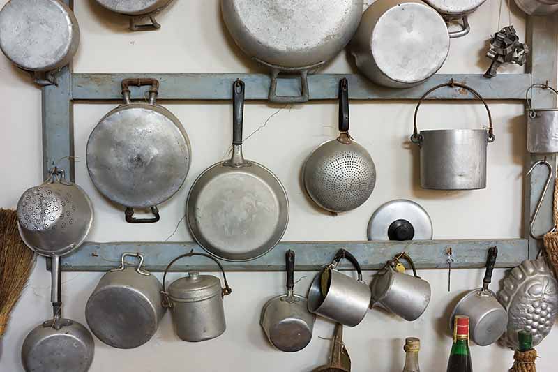 Horizontal image of a wall display with rows of hanging vintage cooking utensils.