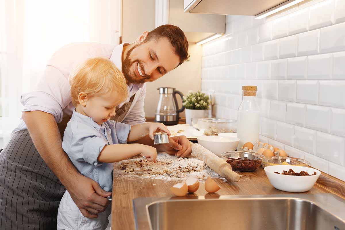 Horizontal image of a father helping a young son prepare food.