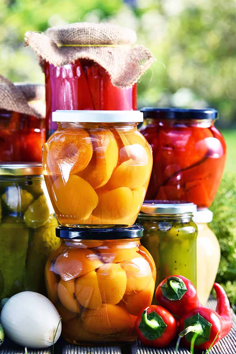 Vertical image of stacks of preserved fruits and vegetables in an outdoor setting.