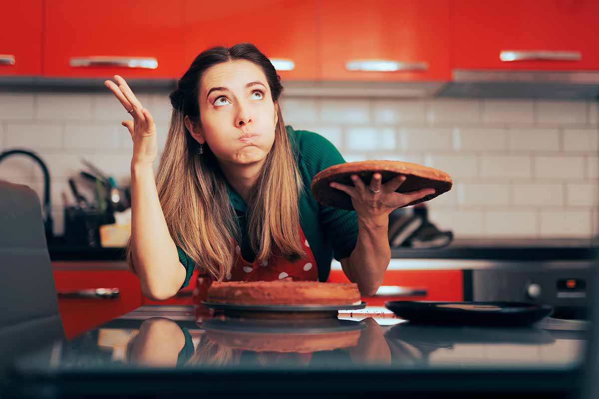 Horizontal image of a stressed woman trying to bake in the kitchen.