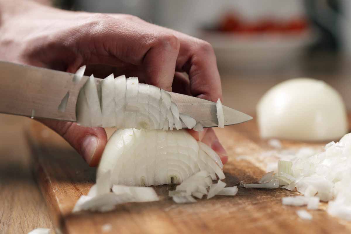 Man,Cutting,White,Onion,With,Knife,,Wide,Photo