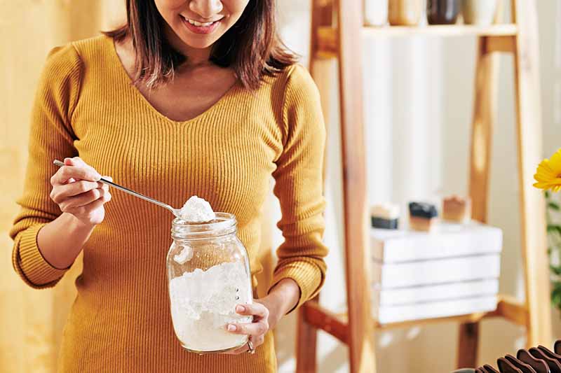 Horizontal image of a woman in a yellow sweater checking her baking soda.