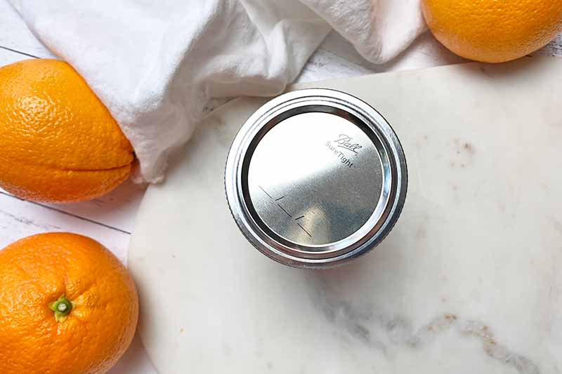 Horizontal image of a canning jar fitted with a metal lid and ring.