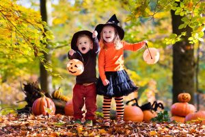 Horizontal image of two children having fun trick-or-treating together outside.