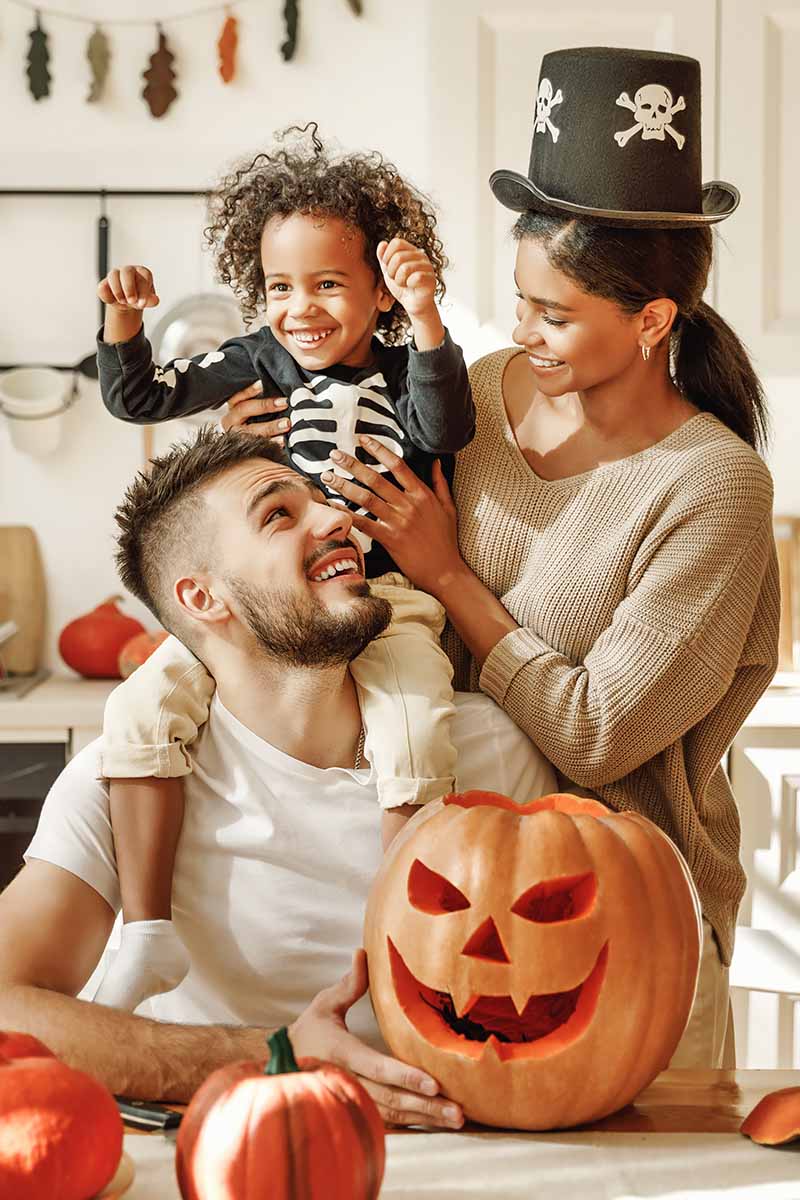 Vertical image of a family carving a pumpkin together.