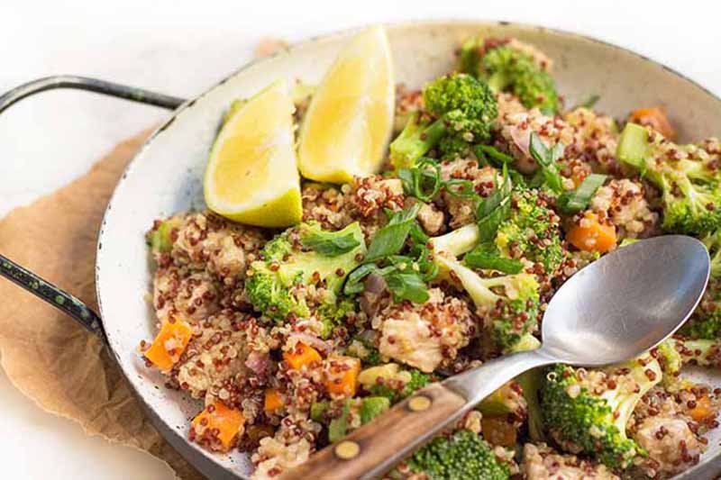 Horizontal image of a mixed dish with quinoa, broccoli, chicken, and carrots.
