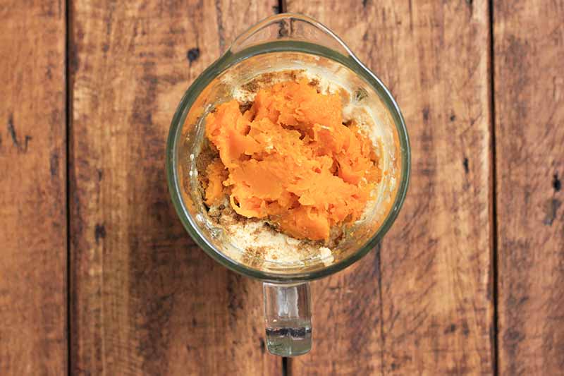 Horizontal image of an orange-colored mashed squash in a blender.
