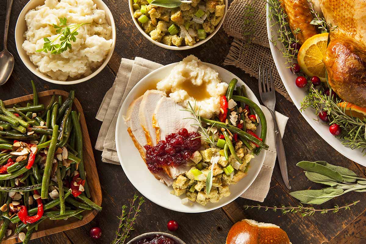 Horizontal top-down image of a complete Thanksgiving dinner spread.