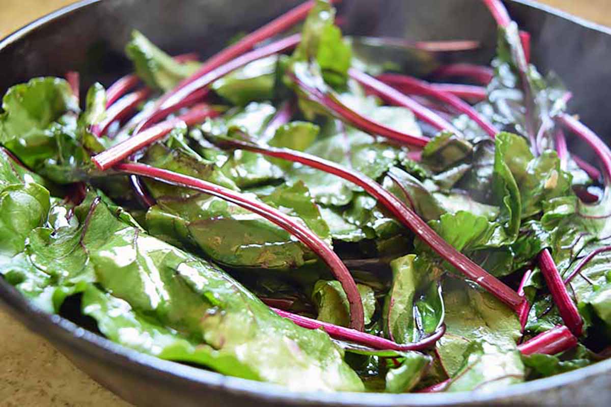 Horizontal close-up image of sauteed greens in a pan.