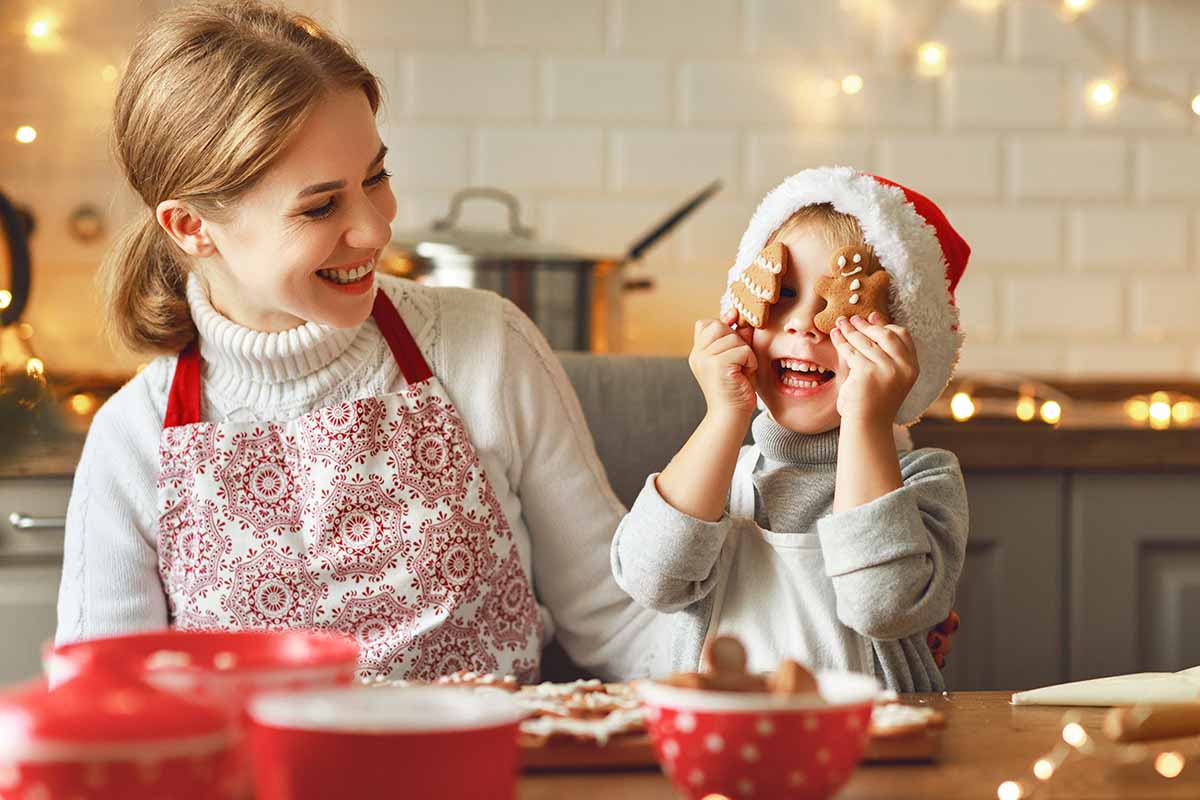 Horizontal image of a mother and son decorating Christmas cookies.