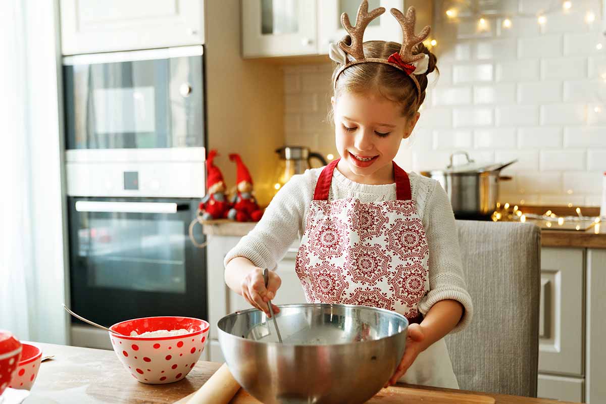 Horizontal image of a girl mixing dough in a bowl.