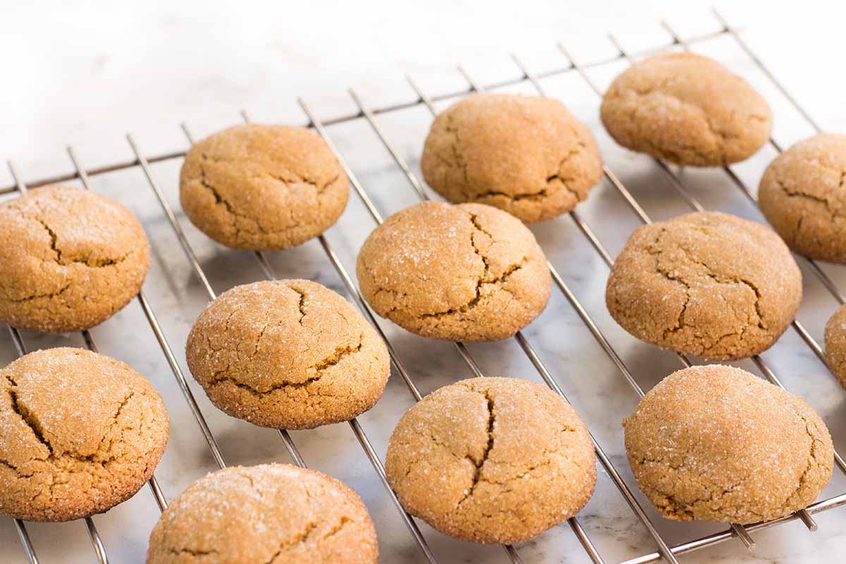 Horizontal image of a cooling rack of sugar-coated molasses cookies.
