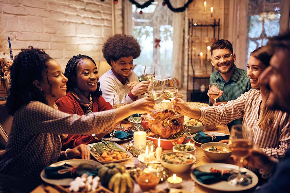Horizontal image of young people toasting with wine at a holiday table at home.