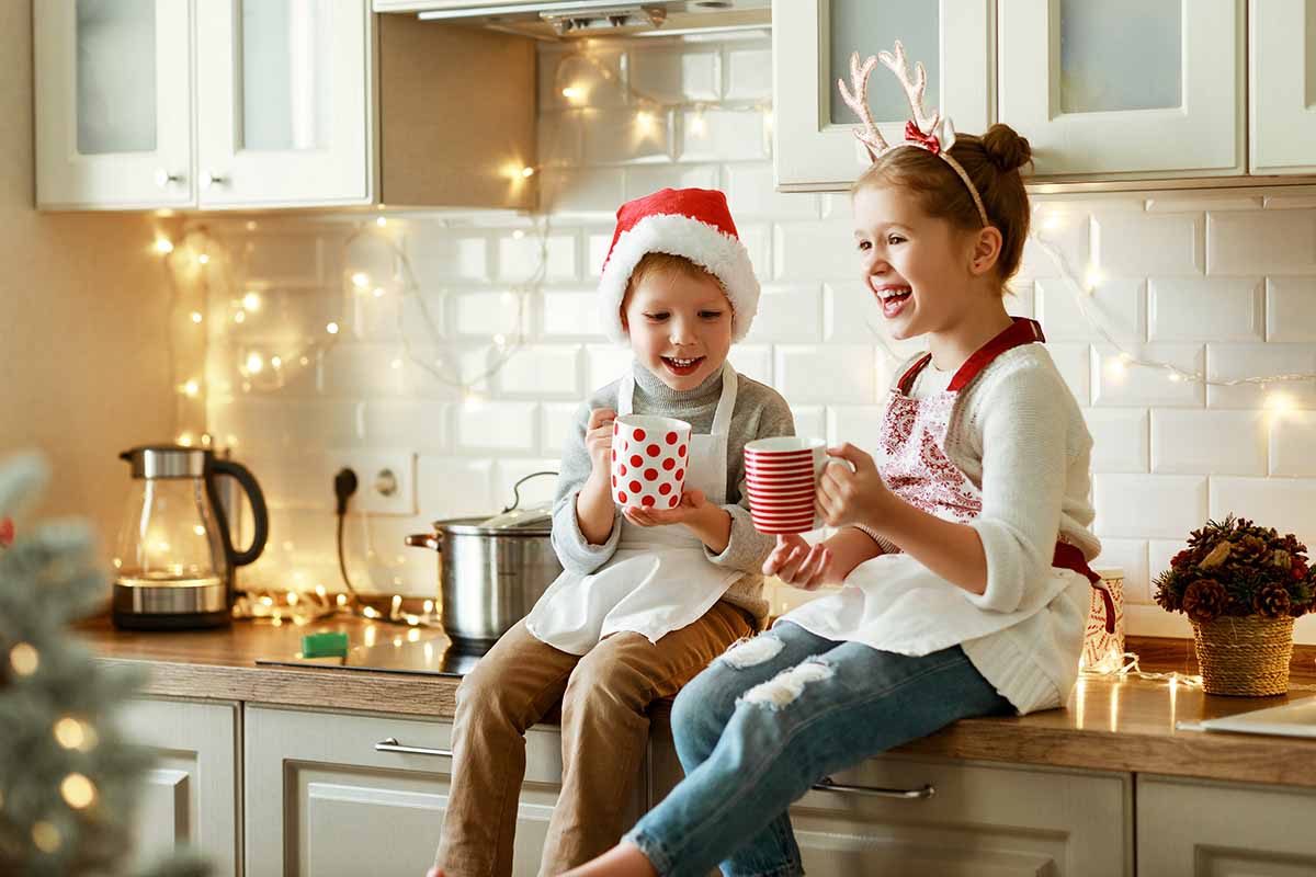Horizontal image of a brother and sister holding mugs wearing Christmas clothes.
