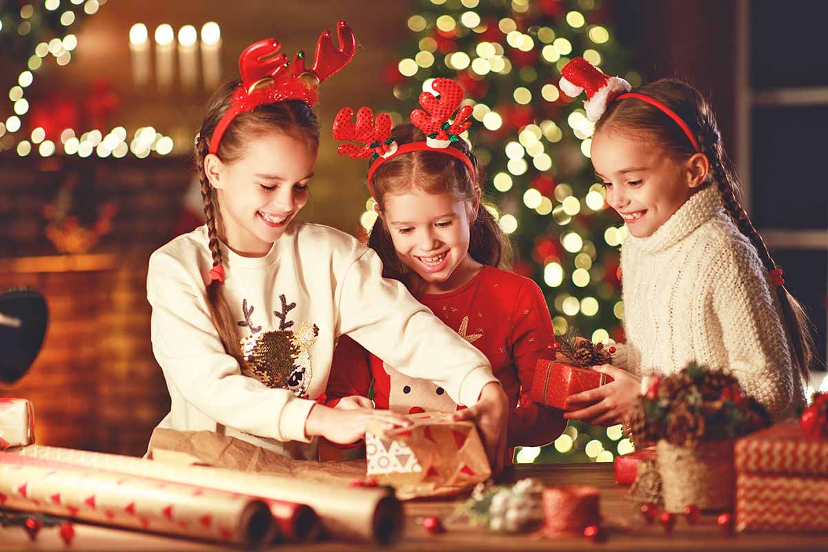 Horizontal image of three girls wrapping presents together.