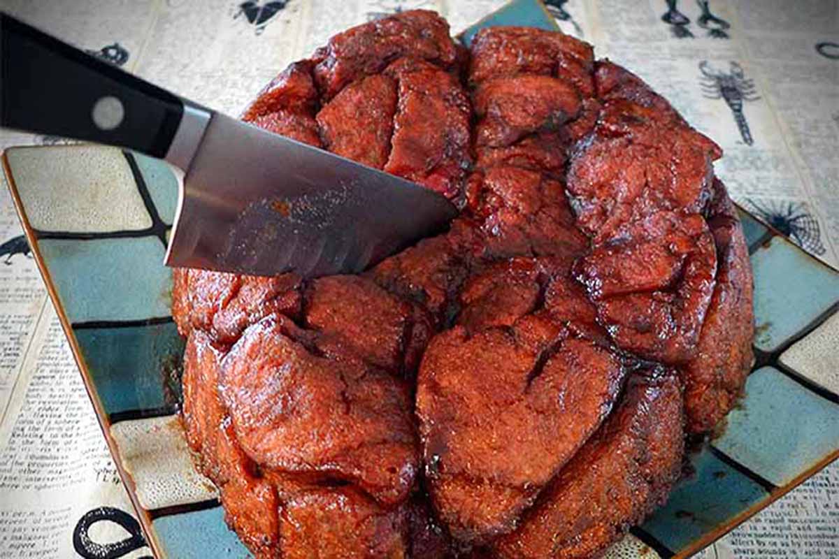 Horizontal image of monkey bread shaped like a brain for Halloween with a chef's knife.