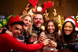 Horizontal image of a group of friends celebrating Christmas together with drinks.