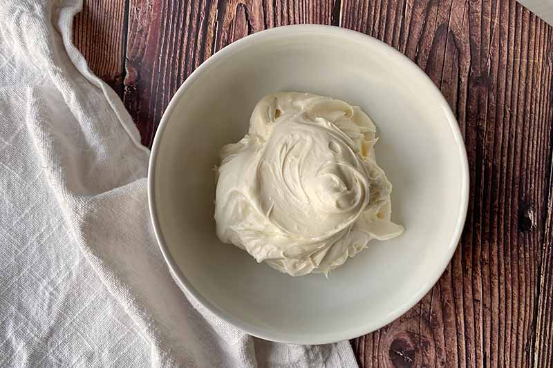 Horizontal image of a cream cheese frosting in a white bowl.