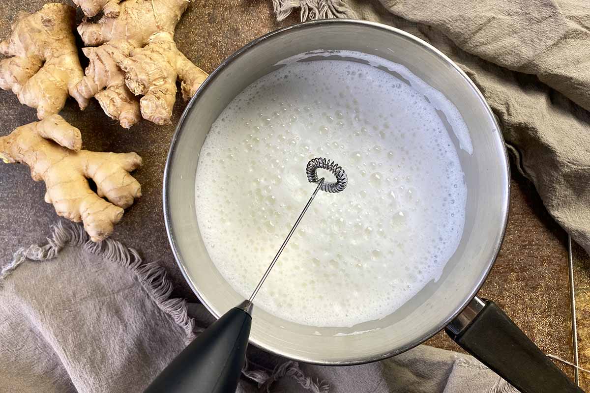Horizontal image of foaming warm milk in a saucepan.
