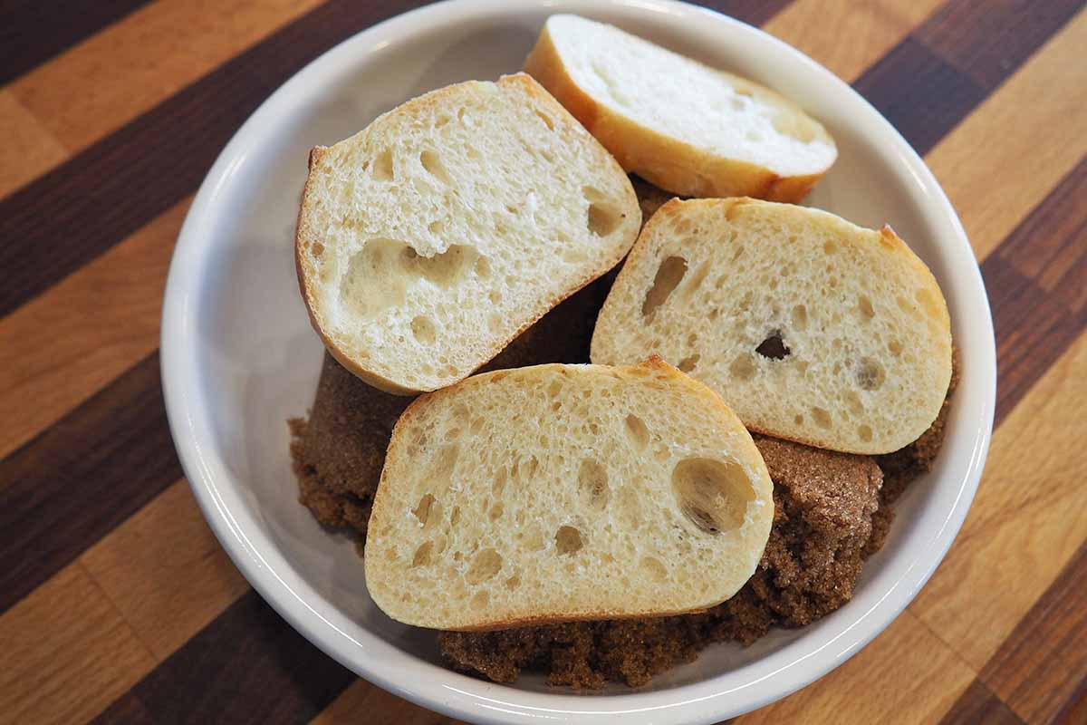 Horizontal image of bread slices in a bowl on top of a dry sweetener on a wooden table.