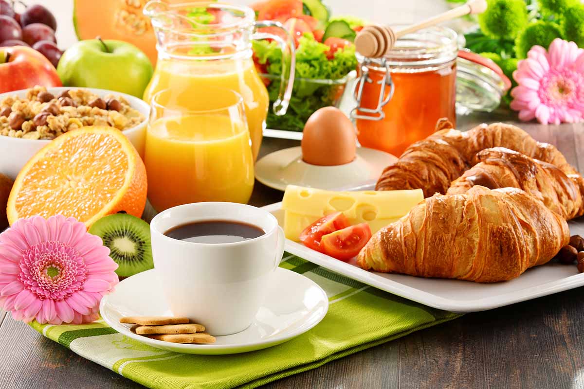 Horizontal image of large brunch spread with fresh flowers and green napkins.