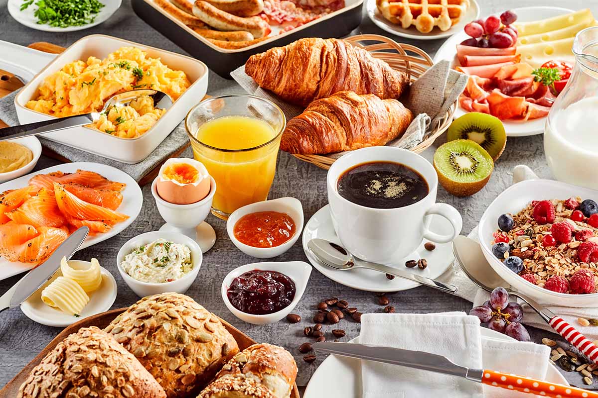 Horizontal image of an assorted brunch food items and drinks on a table.