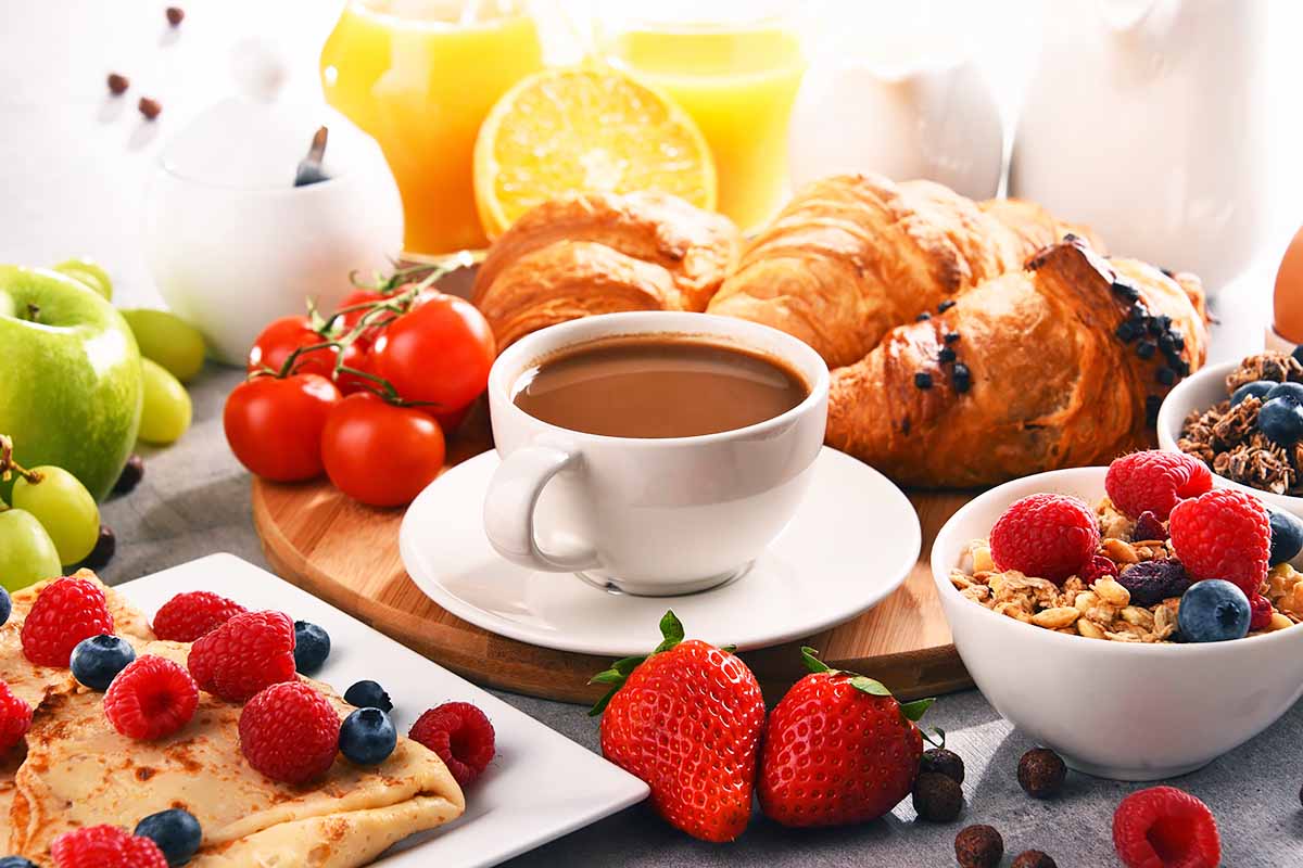 Horizontal image of an assorted brunch food items and drinks on a table.