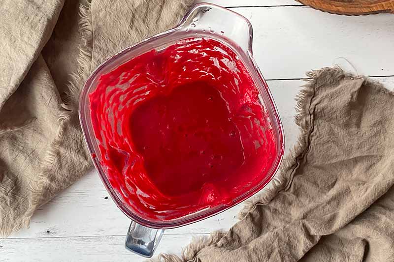 Horizontal image of a bright red puree in a blender.