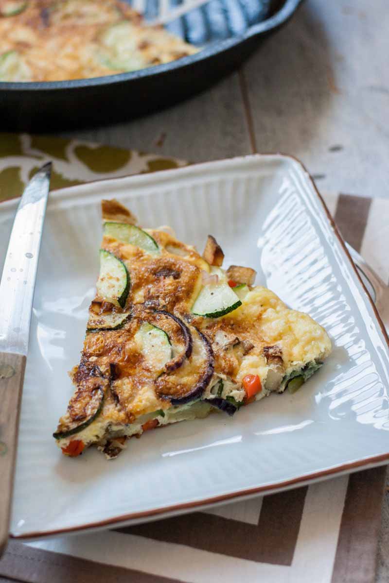 Vertical image of a zucchini and potato frittata wedge.