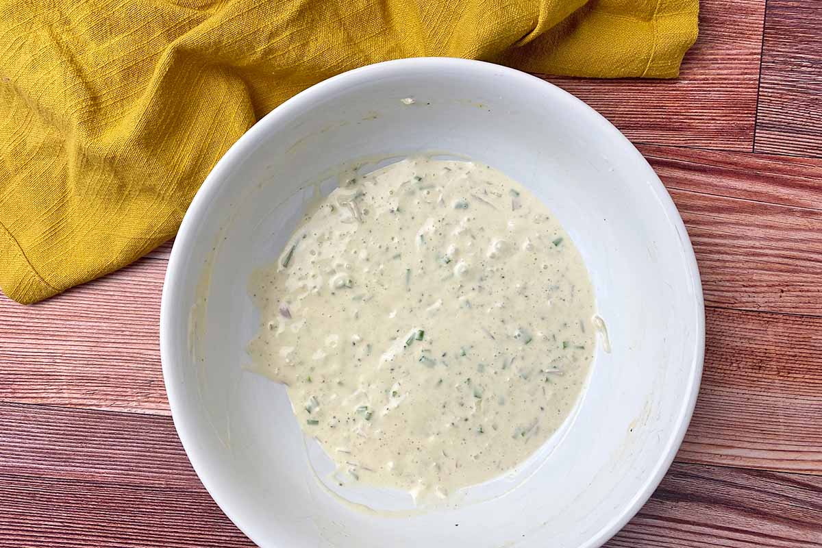 Horizontal image of a creamy dressing in a large white bowl.