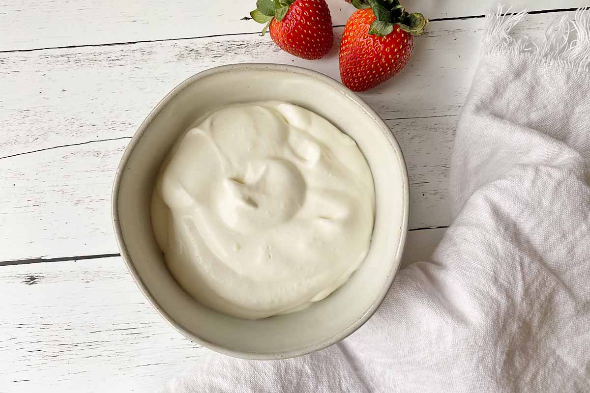 Horizontal image of a white bowl with lightly whipped sweetened cream.