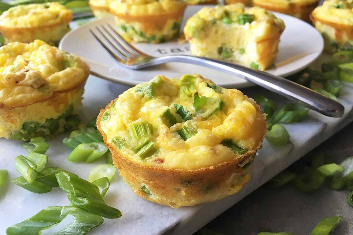 Horizontal image of mini frittatas with green onions and peas.