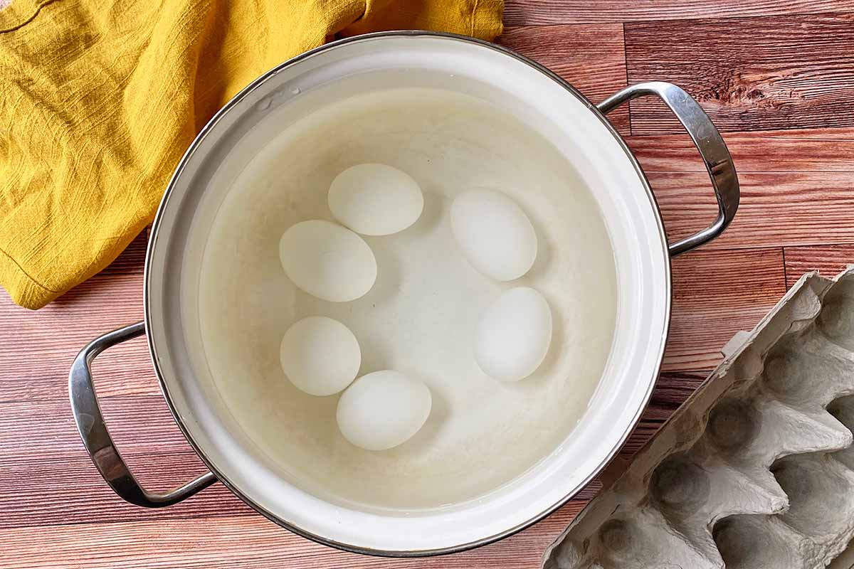 Horizontal image of boiling eggs in a pot of water.