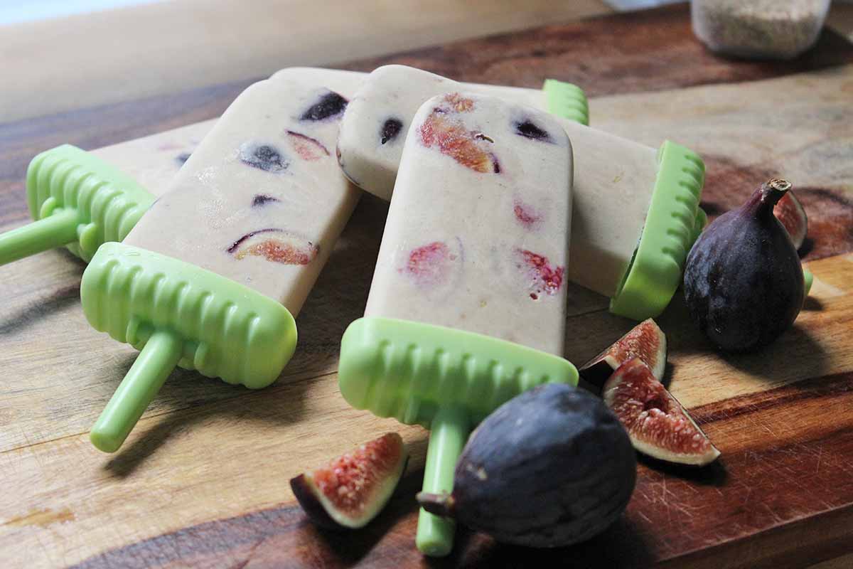 Horizontal image of a pile of popsicles studded with figs.