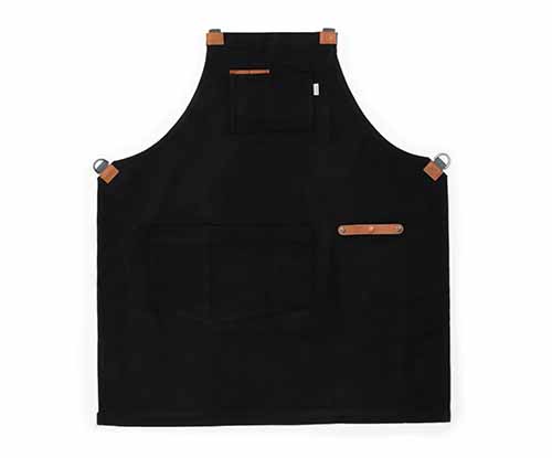 Image of the Barebones Living Chef Apron in black with brown leather accents.