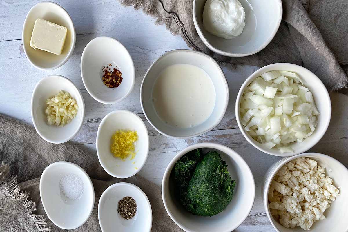 Horizontal image of measured and prepped ingredients in assorted white bowls.