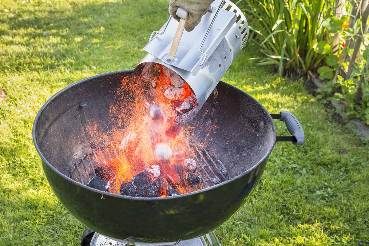 Horizontal image of a chimney starter with hot coals in an outdoor backyard.